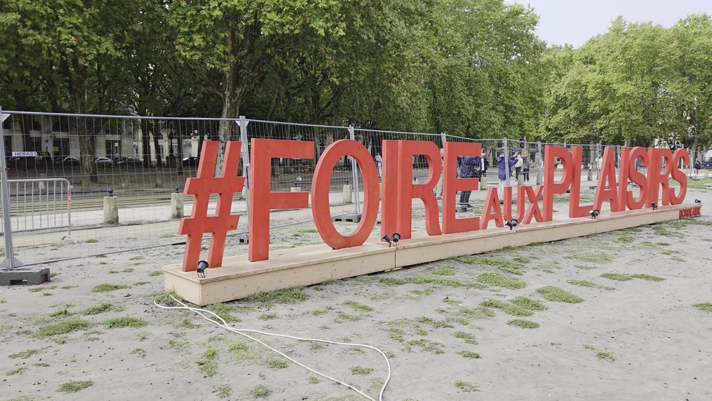 Grandes lettres rouges « Foire aux plaisirs » à l'entrée de la fête, de jour